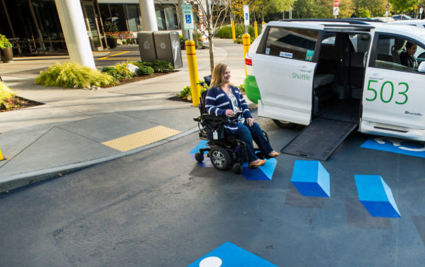 A woman in a powered wheelchair prepares to board a Microsoft shuttle