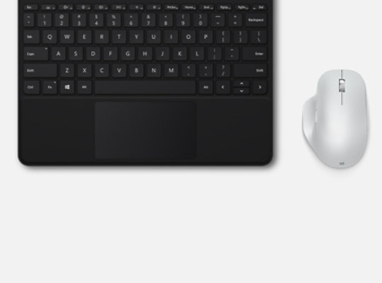 Buz Mavisi Microsoft Bluetooth® Ergonomic Mouse, bir tuş takımının yanında masanın üzerinde duruyor