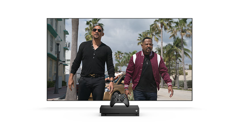 On a TV with an Xbox One in front, Marcus and Mike walk away from a car parked right in front of a palm tree