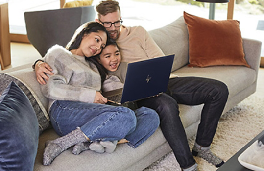 Dad, daughter and son smiling at open Windows 10 laptop on couch