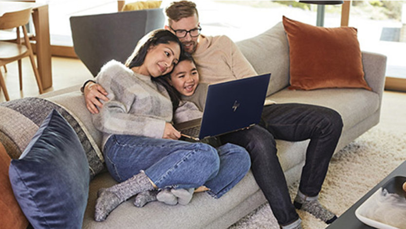 Dad, daughter and son smiling at open Windows 10 laptop on couch