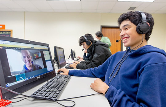 A student smiling while video chatting with a remote volunteer instructor. 