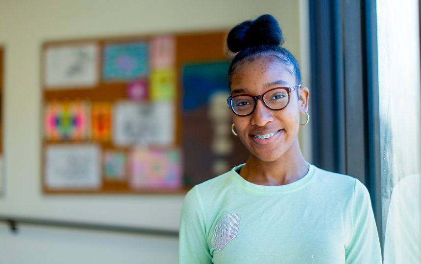 A young person smiling in a classroom.