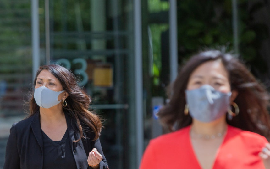 Several people wearing masks walking away from a building.