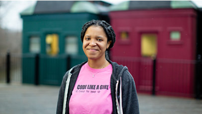A woman smiling outside and wearing a “Code like a girl” shirt