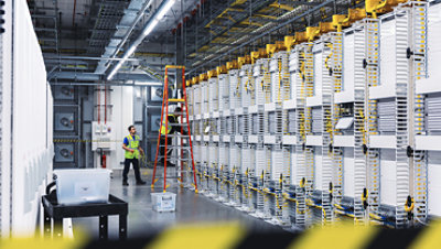 Datacenter employees installing new server rack cables near a ladder with caution tape.