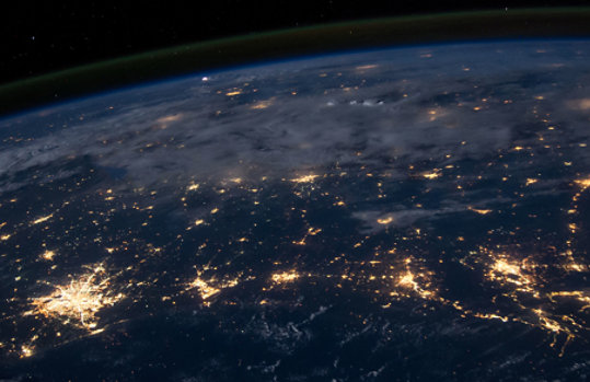 View of the Earth from space with city lights visible against dark sky.