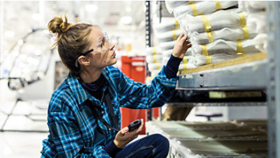 A woman with safety glasses sorting inventory in a warehouse