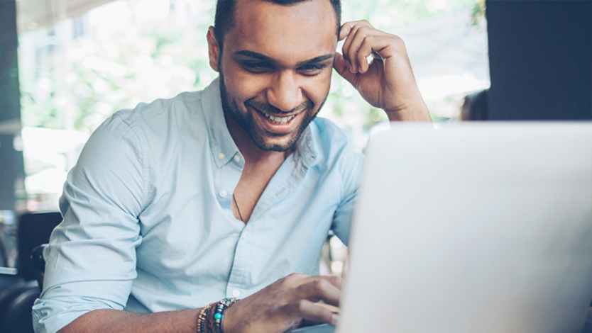 Man smiling and using a Windows laptop