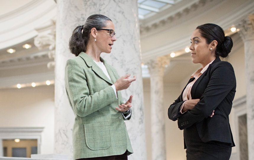  Two female politicians talking in a government building.