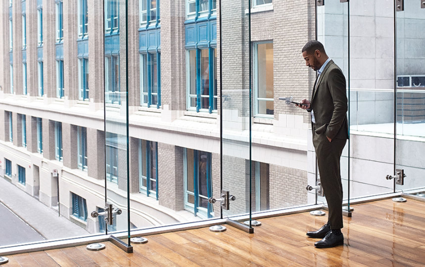  A male business professional in a large foyer is on a mobile device.