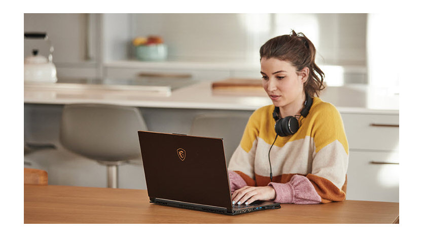 Woman with headphones on working on her computer at home.