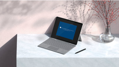 Surface device with type cover and pen on a desktop.