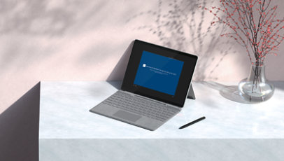 Surface device with type cover and pen on a desktop.