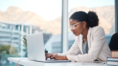 Shot of a young businesswoman using a laptop at her desk in a modern office