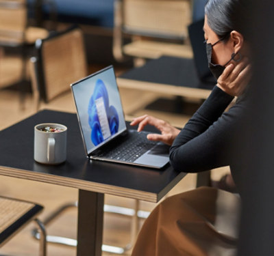 Osoba koja nosi masku koristi laptop koji radi pod operativnim sistemom Windows 11