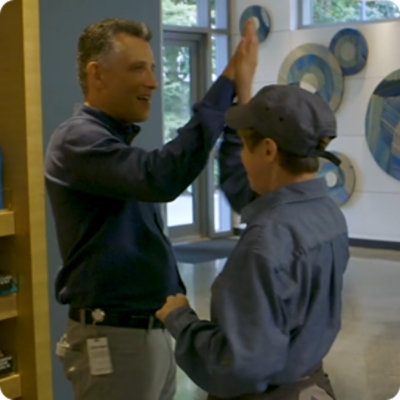 A manager and employee exchange a high five, in a cafe setting.