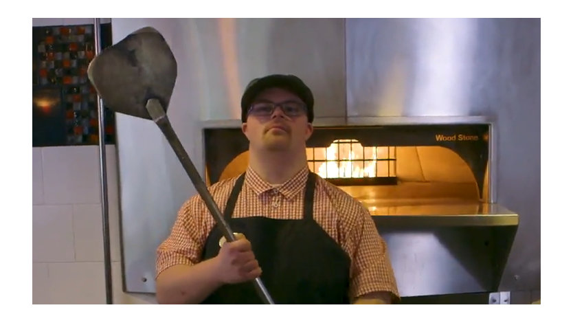 Phillip Thelin holding a pizza peel in front of a café oven