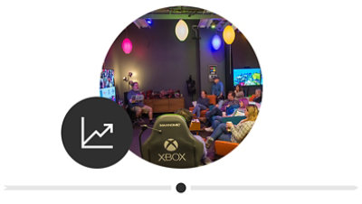 A group of people sitting together under many multicolored lights, and collaborating in the original Inclusive Tech Lab. 