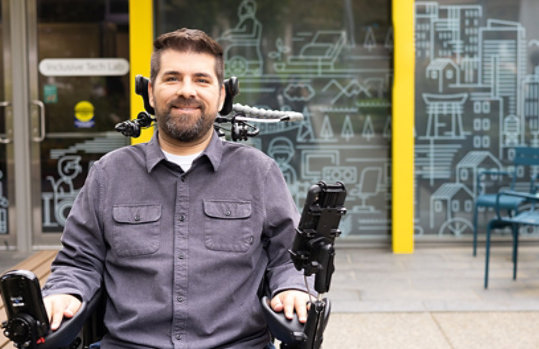 A smiling man sitting in his wheelchair outside the Inclusive Tech Lab