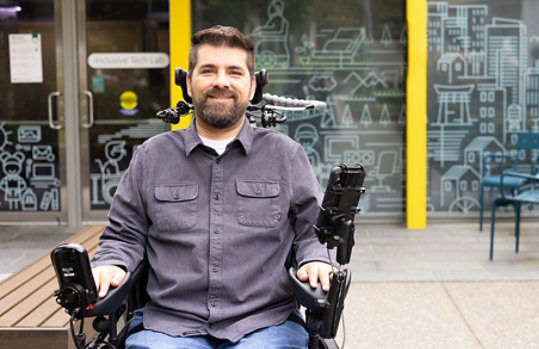 A smiling man sitting in his wheelchair outside the Inclusive Tech Lab