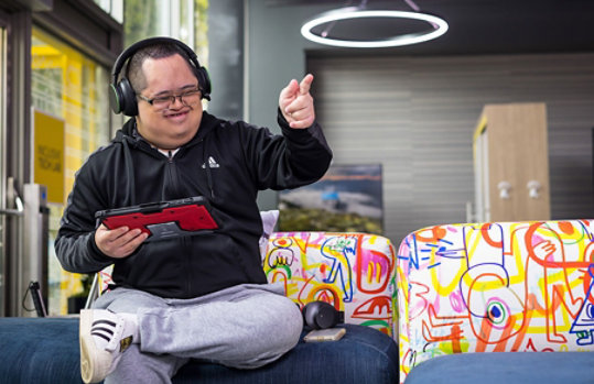 A man listening to music on his headphones while working on his tablet. 