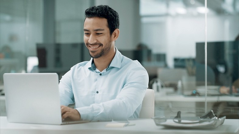 Homme souriant travaillant sur un ordinateur portable.