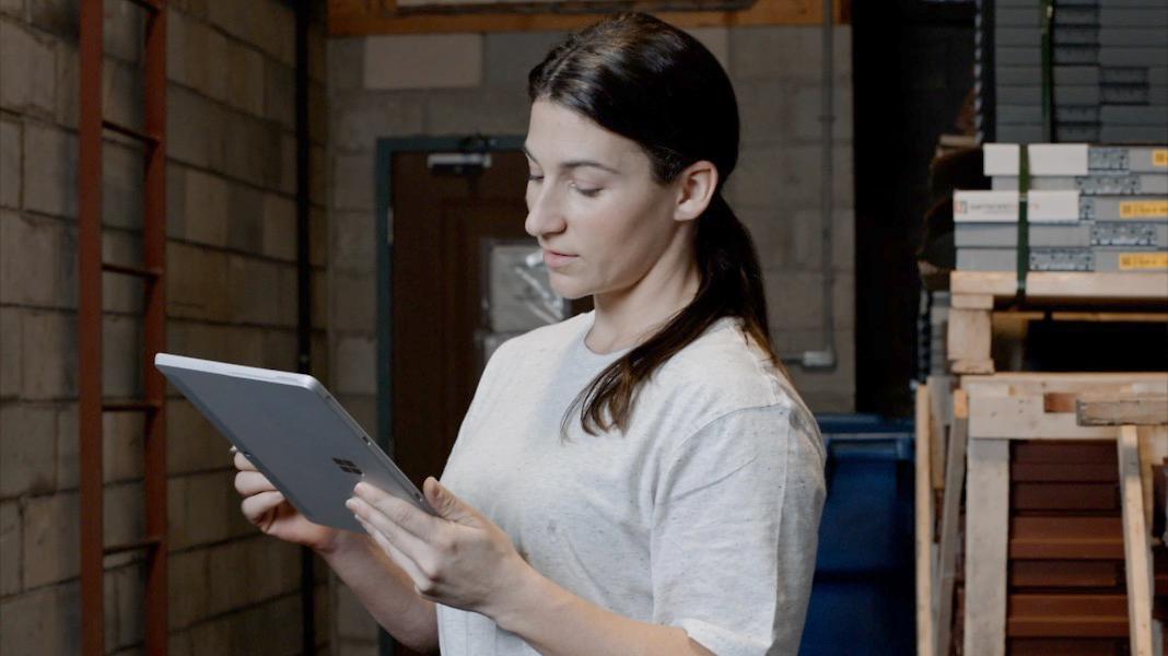 Woman in warehouse holding Microsoft Surface