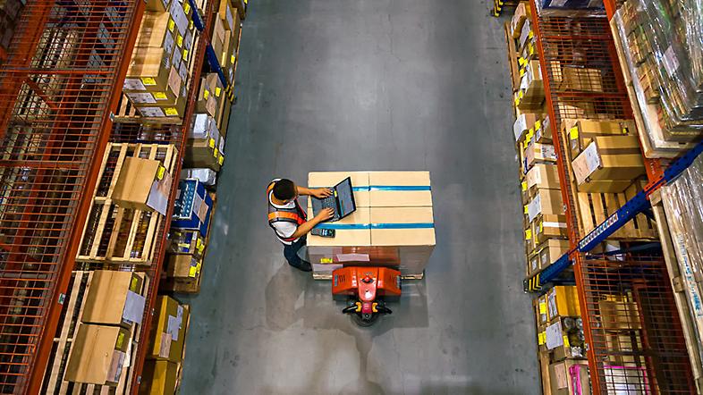 Overhead view of a worker on a laptop in a warehouse