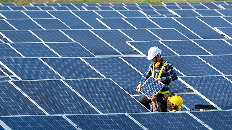 Two people installing solar panels in a field.