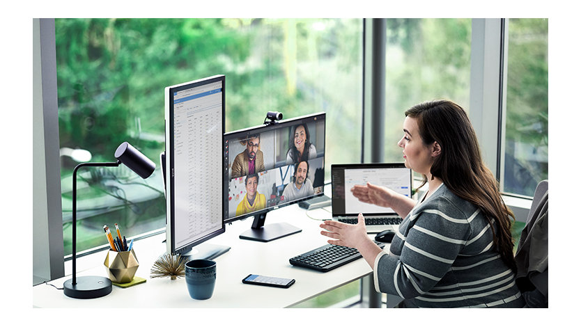 女子在桌前使用多台裝置辦公，並執行 Microsoft Teams 電話會議。