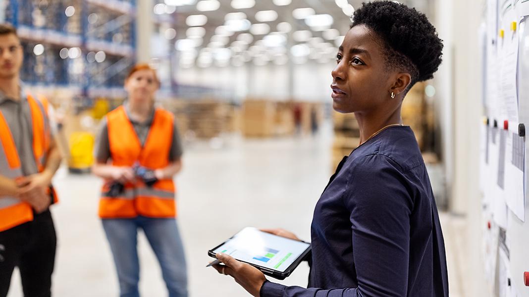 Woman speaking to warehouse workers holding Microsoft Surface
