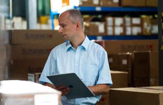Man working on Surface laptop in a warehouse.