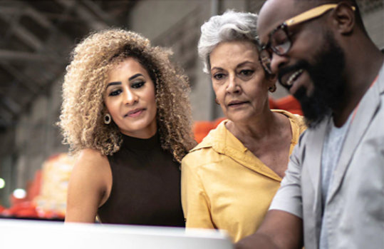 Two woman and a man working together looking at laptop.