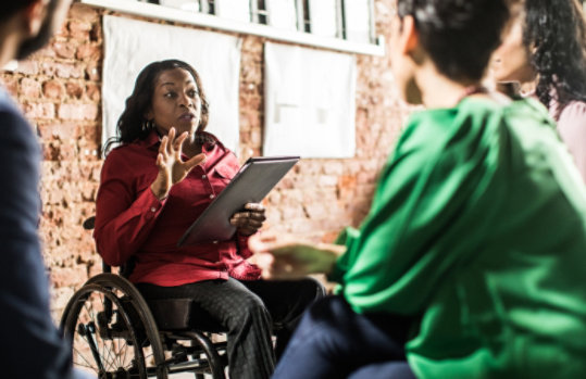 Businesswoman in wheelchair leading group discussion in creative office.