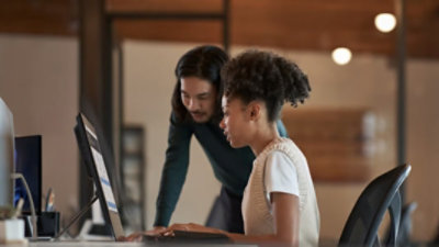 Kaksi henkilöä katsoo pöytänäyttöä.