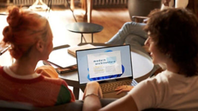 Kaksi henkilöä katselee artikkelia nimeltä Moderni arkkitehtuuri kannettavalla tietokoneella, jossa on Windows 11.