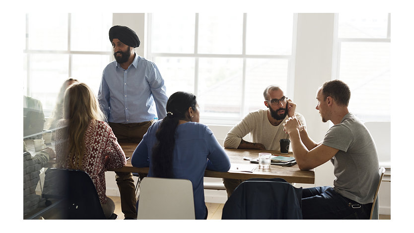 A group gathers around a table having a meeting in an office.