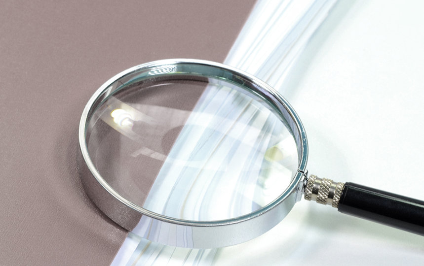 File with loads of paper and magnifying glass.