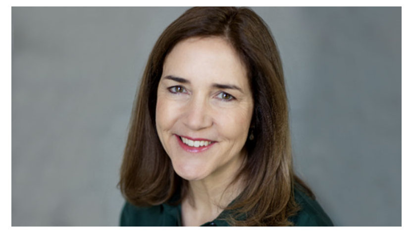 A headshot image of Kristen Roby Dimlow smiling in front of a grey background 