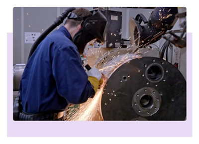 Persona metināšanas apģērbā strādā ar lielu aprīkojumu.