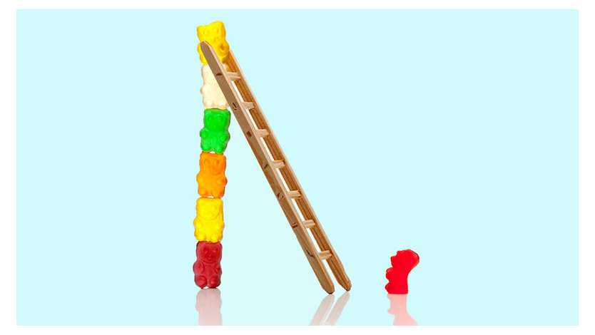 A photograph of a stack of gummy bears holding up a ladder for a single gummy bear