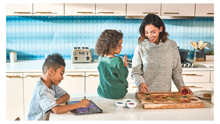 A smiling woman preparing a meal in the kitchen with her children