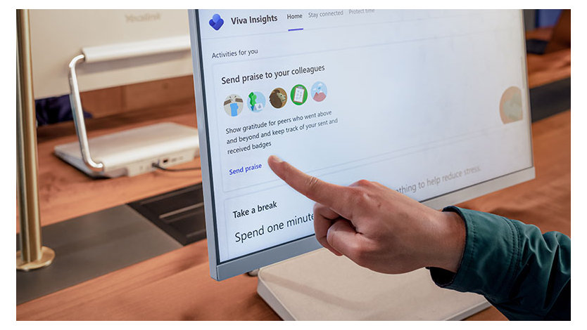 A close up of a hand pointing a computer monitor screen at the option to send praise to their colleagues on the Viva Insights dashboard