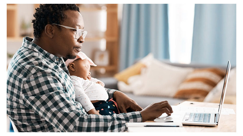 A person using their laptop while sitting at home with their baby.