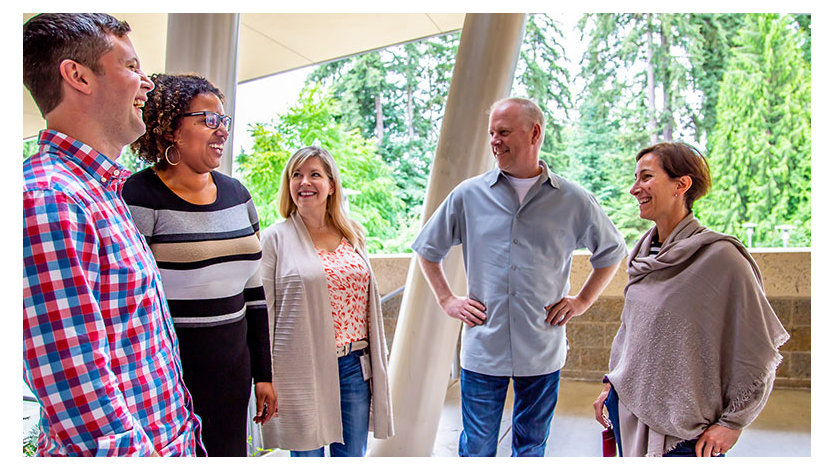 A group of people standing in a half circle having a conversation