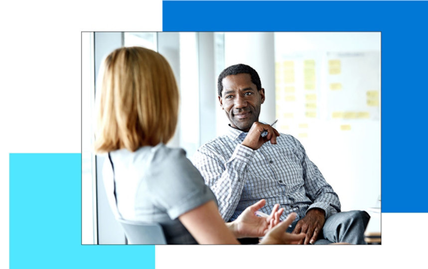 A man sitting in a chair listening to his coworker 