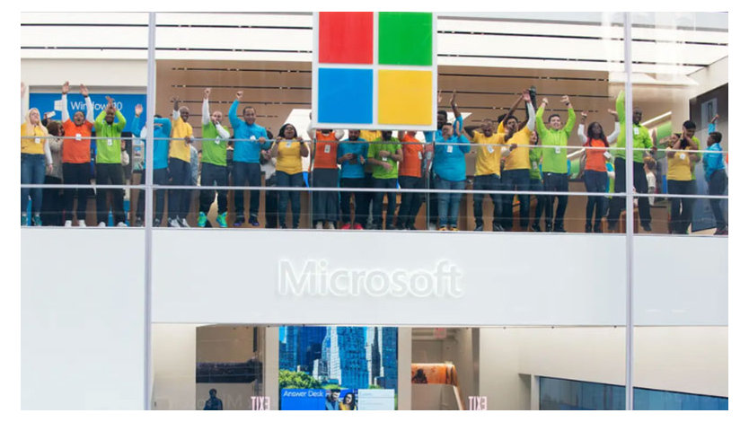 A photograph inside a Microsoft building with employees celebrating in brightly colored T-shirts.