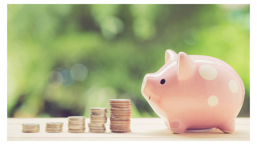 A photo of a pink piggy bank with stacks of coins in front of it.