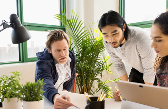 Drei Personen arbeiten im Büro zusammen.